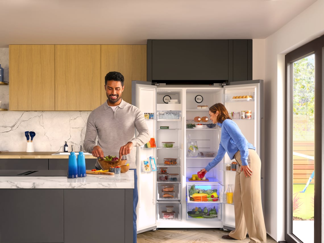 Couple in kitchen with american style fridge freezer open